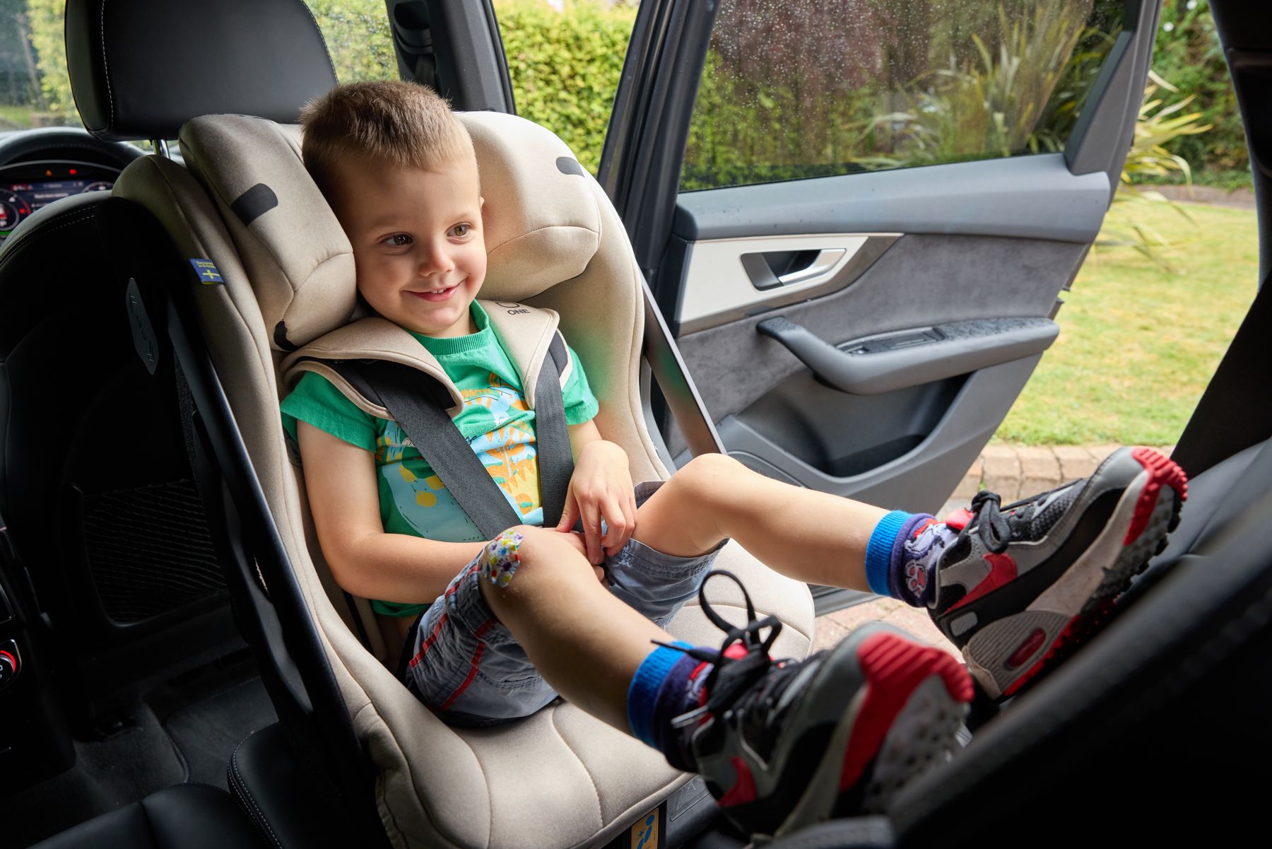 A smiling boy in a high-back car seat